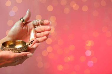Diwali kutlaması. Elinde yanan diya lambası tutan bir kadın. Arka planda bulanık ışıklar var. Yakın plan. Metin için boşluk