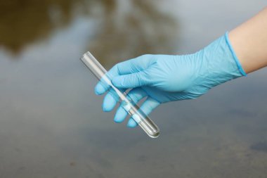 Su kalitesinin incelenmesi. Araştırma görevlisi test tüpünü dışarıda tutuyor, yakın plan.
