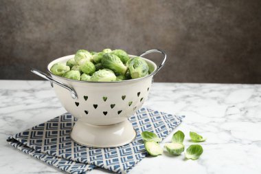 Taze Brüksel lahanaları beyaz mermer masa üzerinde metal kevgir, metin için yer