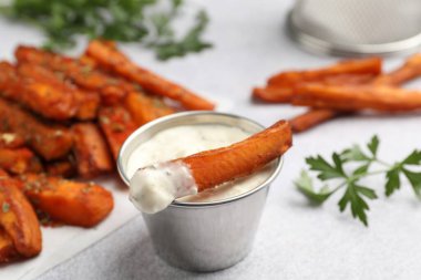 Tatlı patates kızartması, sos ve maydanoz açık gri masada, yakın plan.