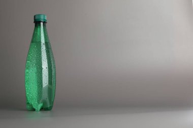 Gri arka planda plastik su şişesi. Metin için boşluk
