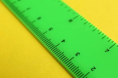 Sarı arka planda bir yeşil cetvel, yakın plan.