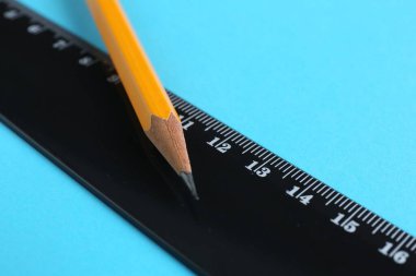 Açık mavi arkaplanda cetvel ve kalem, yakın plan