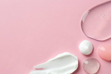 Pembe arka planda farklı kozmetik ürünlerinin kokusu. Metin için boşluk