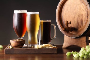 Farklı tipte bira, fıçı, aperatif ve ahşap masada taze zıpzıp bardakları.