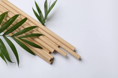 Bambu pipetleri ve beyaz arka planda palmiye yaprakları, üst manzara. Metin için boşluk