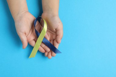 Arka planda sarı ve mavi kurdeleli çocuk, üst manzara. Down sendromu farkındalığı