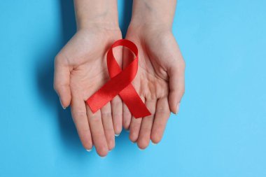 Açık mavi arka planda kırmızı kurdeleli kadın, üst manzara. HIV (AIDS) Hastalık Bilinci