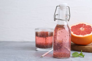 Gri masadaki cam şişe Chia tohumu ve greyfurtlu içecek. Metin için boşluk