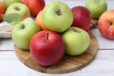 Beyaz ahşap masada farklı olgun elmalar, yakın plan.