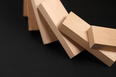 Domino etkisi. Tahta bloklar siyah arkaplan üzerine düşüyor, yakın plan
