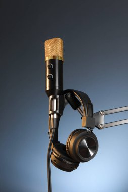 Koyu arka planda mikrofon ve kulaklıkla kalın, düşük açılı görüş. Ses kaydı ve takviye