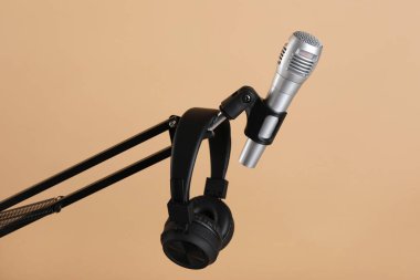 Bej arka planda mikrofon ve kulaklıkla durun. Ses kaydı ve takviye