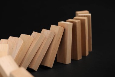 Domino etkisi. Tahta bloklar siyah arkaplan üzerine düşüyor, yakın plan