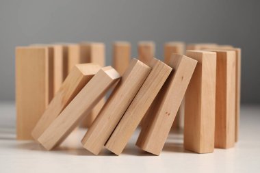 Domino etkisi. Tahta bloklar beyaz masaya düşüyor, yakın plan.