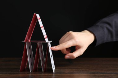 Ahşap masadaki iskambil kağıtlarının olduğu evi yok eden kadın, yakın plan.