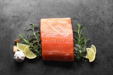 Gri masada taze somon, limon ve baharat var.