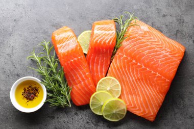 Gri masada taze somon, limon ve baharat parçaları.