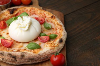 Tahta masada burrata peynirli, fesleğenli ve domatesli lezzetli pizza.
