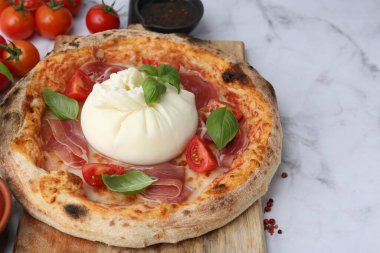 Burrata peynirli lezzetli pizza, fesleğen, domates ve jambon beyaz mermer masada, yakın plan.