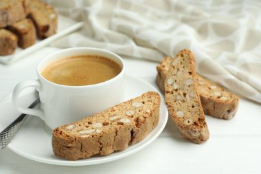 Geleneksel İtalyan badem bisküvileri (Cantucci) ve beyaz ahşap masa üzerinde kahve, yakın plan.