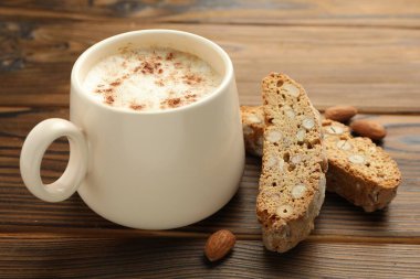 Geleneksel İtalyan badem bisküvileri (Cantucci), fındık ve bir fincan kahve ahşap masada, yakın plan.