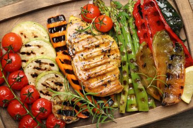 Lezzetli ızgara sebzeler ve ahşap masada tavuk göğsü.