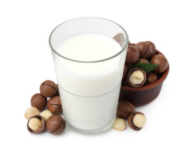 Beyaz üzerine izole edilmiş bir bardak Macadamia sütü ve fındık.