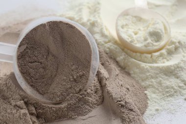 Beyaz arka planda protein tozları ve kepçeler, yakın plan