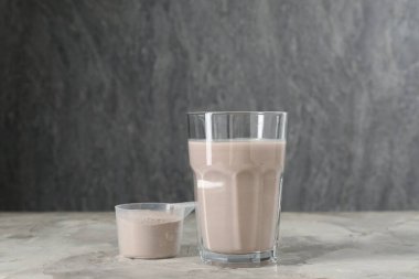Bardakta leziz protein karışımı ve gri masada toz.