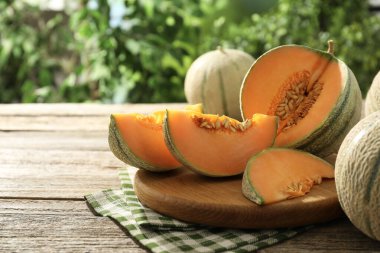 Açık havada, ahşap masada olgun kavunlar var.