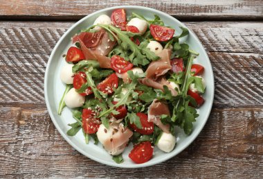 Lezzetli salata roka, mozzarella peyniri, domates ve jamon ahşap masa, üst manzara.