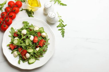 Lezzetli salata roka, mozzarella, domates ve beyaz mermer masada salatalık, düz yatak. Metin için boşluk