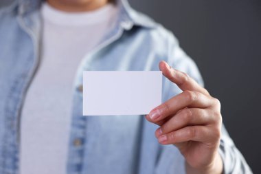 Gri arka planda boş kartviziti olan bir kadın, yakın plan. Tasarım için model