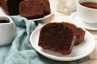 Lezzetli çikolatalı kek dilimleri ve beyaz ahşap masada çay, yakın plan.