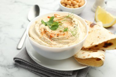 Kırmızı biberli lezzetli humus, beyaz mermer masada pide ve nohut, yakın plan.