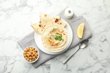 Kırmızı biberli enfes humus, beyaz mermer masada pide ve nohut, üst manzara.