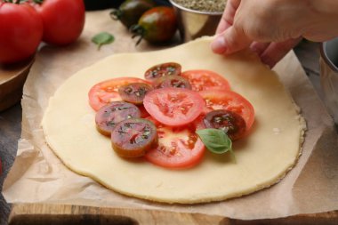 Ahşap masada domates ve fesleğenle galette yapan kadın, yakın plan.