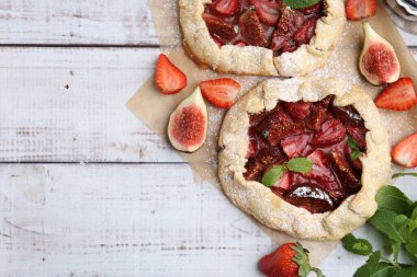 Çilekli lezzetli galetler, incir ve nane şekerli ahşap masa, düz yatak. Metin için boşluk
