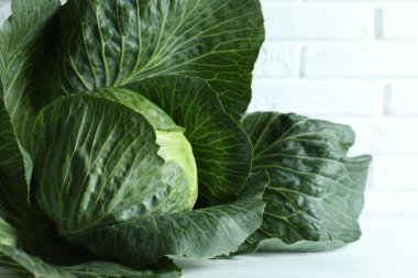 Beyaz ahşap masada olgun bir lahana başı, yakın plan.