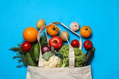 Vejetaryen ürünlerin teslimatı. Farklı sebzeler ve açık mavi arka planda meyveler, üst manzara.