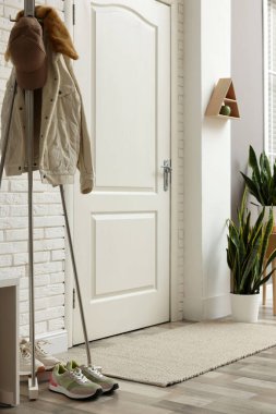 Koridorda ceketli, şapkalı ve spor ayakkabılı metal askı.