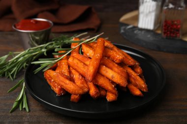 Tatlı patates kızartması ve biberiye ahşap masada, yakın plan.