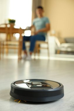 Robotik süpürge zemini temizlerken erkekler evde rahatlarken, seçici odaklanma