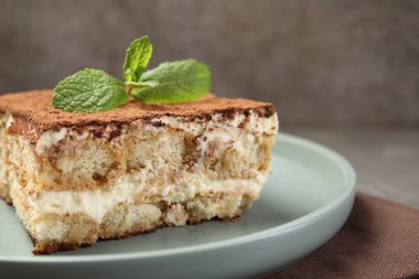 Bir parça lezzetli tiramisu. Masada taze nane var. Yakın plan.