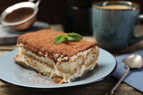 Piece of tasty tiramisu on wooden table, closeup