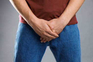 Cinsel yolla bulaşan hastalıklar. Gri arka planda semptomlardan muzdarip bir adam, yakın plan