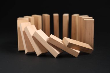Domino etkisi. Tahta bloklar siyah arkaplan üzerine düşüyor, yakın plan