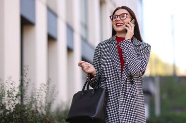 Şık takım elbiseli güzel bir kadın dışarıda akıllı telefondan konuşuyor. Metin için boşluk
