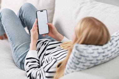 Evde kanepede Smartphone kullanan kadın